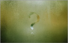 A question mark written into condensation on a window.