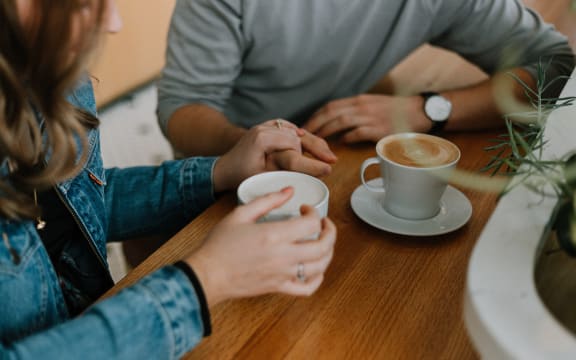 Image of two people having coffee together, their hands and the coffee are visible.