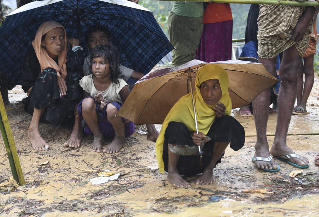 (FILES) In this file photo taken on September 17, 2017 Rohingya refugees protect themselves from rain in Balukhali refugee camp near the Bangladesh town of Gumdhum.