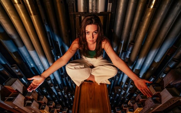 Organist Zosia Herlihy-O'Brien sits cross-legged inside the workings of the pipe organ at St Mark's Church, Remuera.