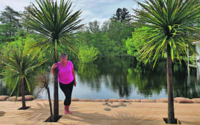Christine McDonald stands on the deck of her villa home on Manawahe Road overlooking what used to be her lawn and some half-drowned trees.