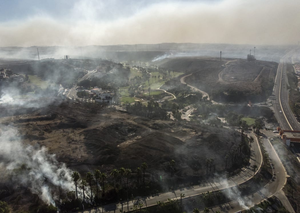 Aerial view of palms and brush burning at Real Del Mar residential outskirts Tijuana, Baja, California state.