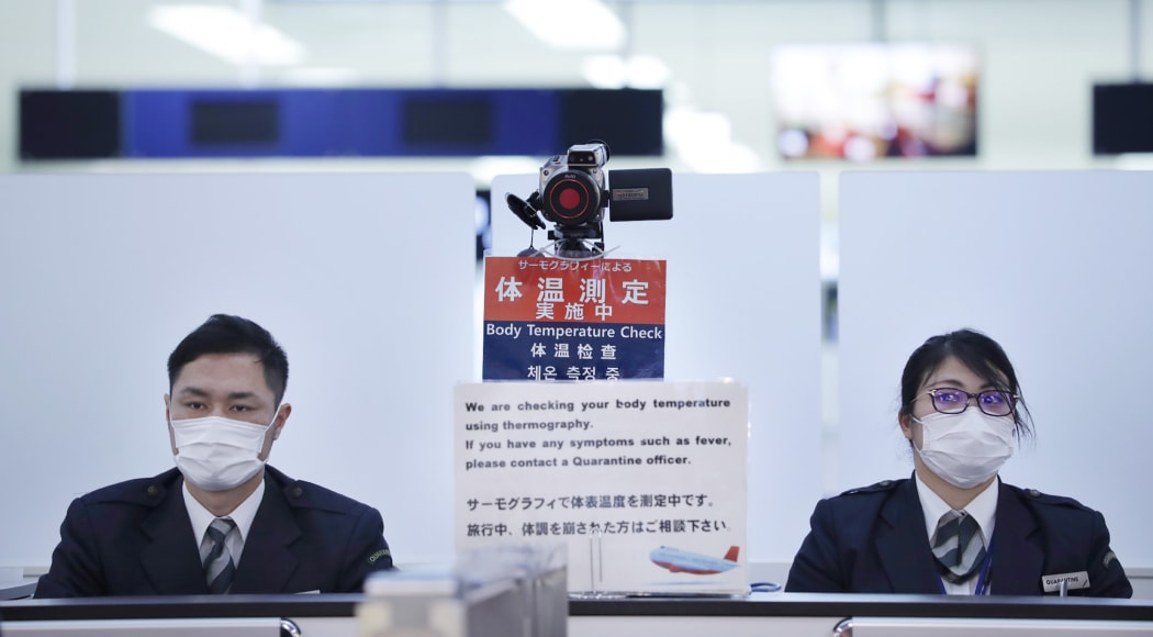 Officers work at a health screening station as they observe passengers arriving on a flight from Wuhan, China, where a SARS-like virus was discovered, at Narita airport, Japan.