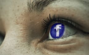 Facebook logo reflected in a woman's eye