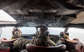 A P-3K2 Orion aircraft flies over an area of Tonga that shows the heavy ash fall from the recent volcanic eruption within the Tongan Islands.