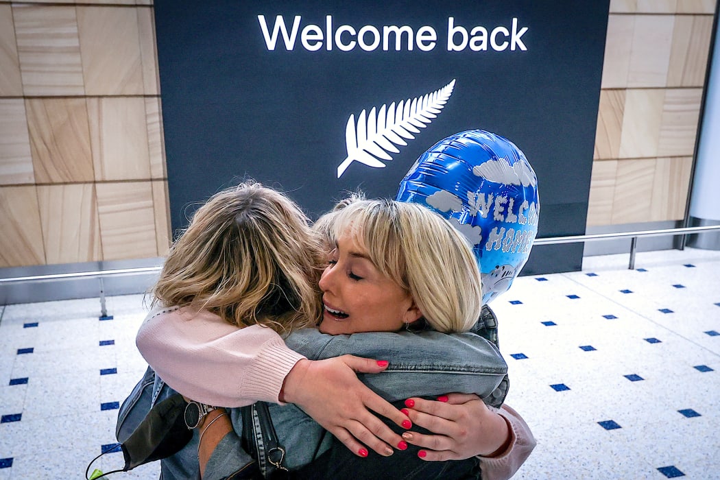 A passenger hugs family members upon arrival from New Zealand at Sydney International Airport.