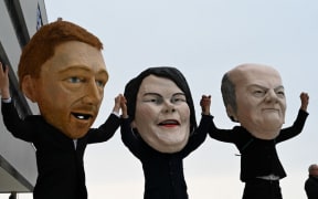 masks of (L-R) the leader of Germany's free democratic FDP party Christian Lindner, the co-leader of Germany's Greens (Die Gruenen) Annalena Baerbock and German Finance Minister, Vice-Chancellor and the Social Democratic SPD Party's candidate for chancellor Olaf Scholz