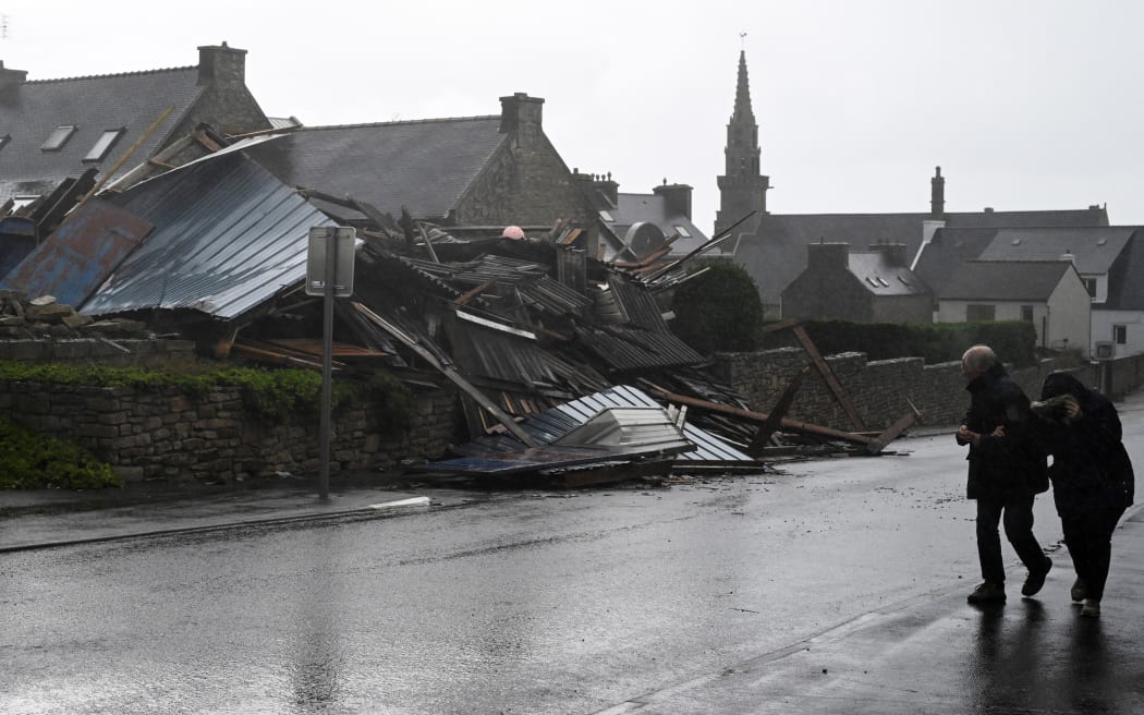 Pedestrians walk past a destroyed warehouse in Porspoder, western France, on November 2, 2023, as the storm Ciaran hits the region. Much of northwestern Europe went on high alert on November 1, 2023 as a storm dubbed Ciaran threatened to bring gale-force winds and extreme rainfall to the region.