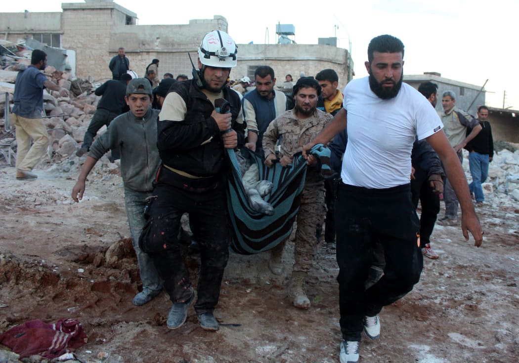 Civil defence members and civilians carry a body from debris airstrikes over residential area in Batebo district of Aleppo.