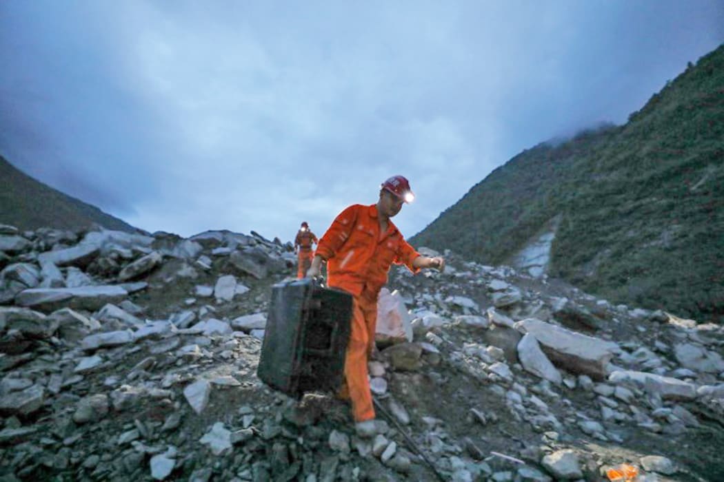 Rescuers work at the accident site after a landslide occurred in Xinmo Village.