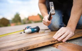 A worker hammers down timber for a house's deck.