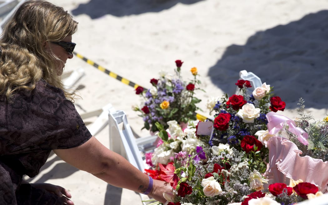 A woman lays flowers at the site of a shooting attack on the beach in front of the Riu Imperial Marhaba Hotel.