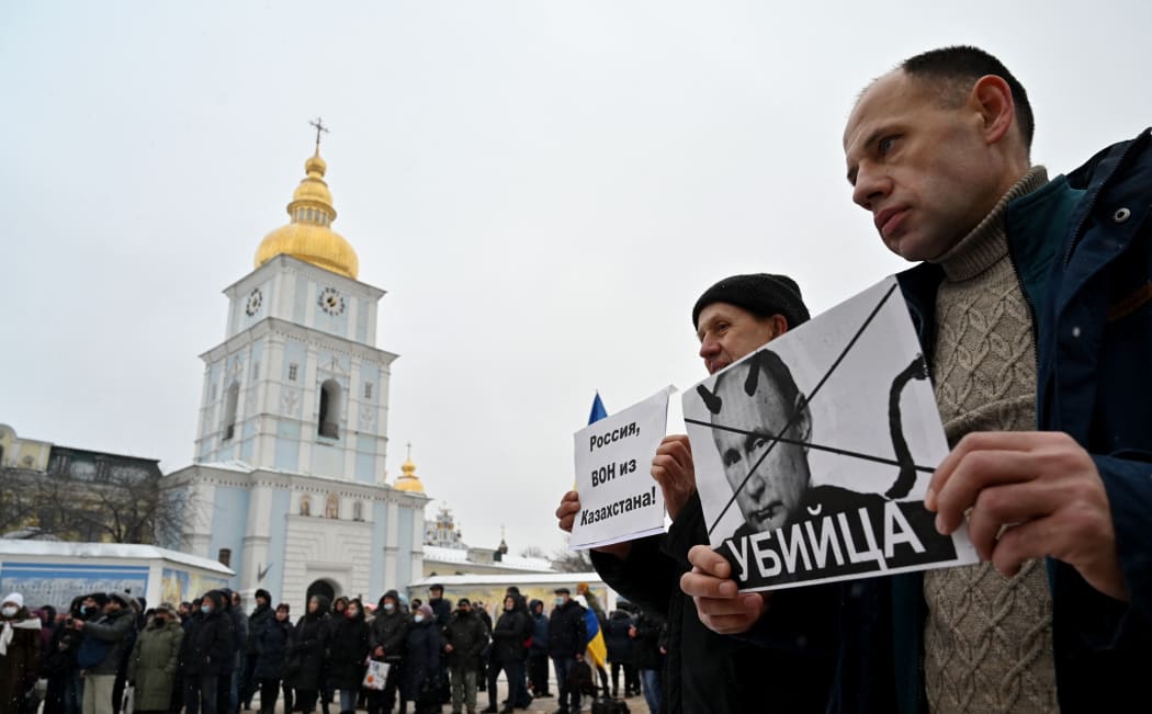 People hold placards depicting Russian president Vladimir Putin signed "Killer" and another one reading "Russia, go out from Kazakhstan!" during an action dubbed #SayNOtoPutin in Kyiv.