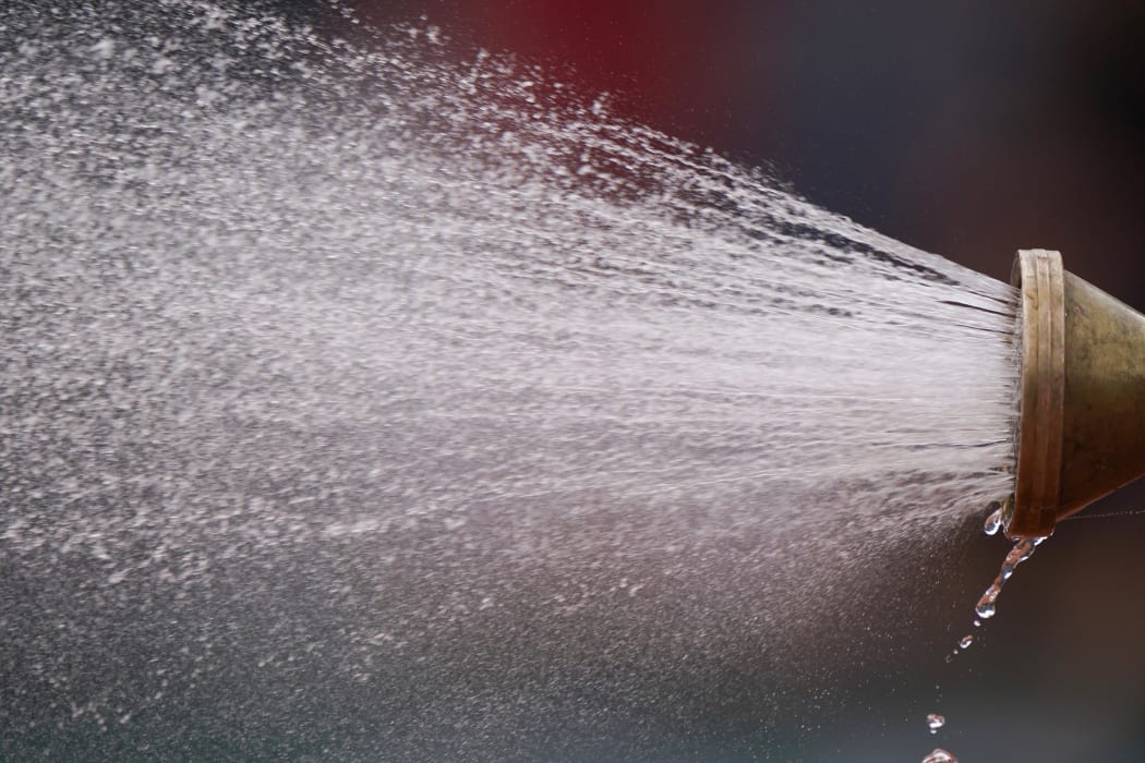 Groundstaff members sprays water on the tennis court during the men's singles first round match on day 1 of The Roland Garros 2019 French Open tennis tournament in Paris on May 26, 2019. (Photo by Kenzo TRIBOUILLARD / AFP)