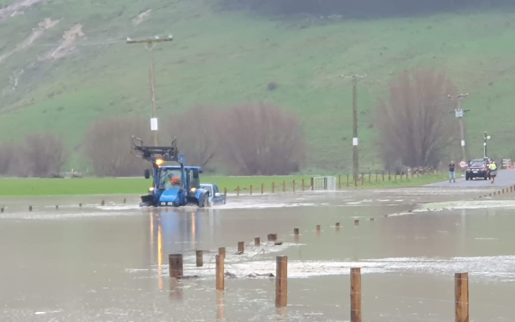 A tractor towing a vehicle through a flooded field near the township of Te Karaka on 22 June 2023.