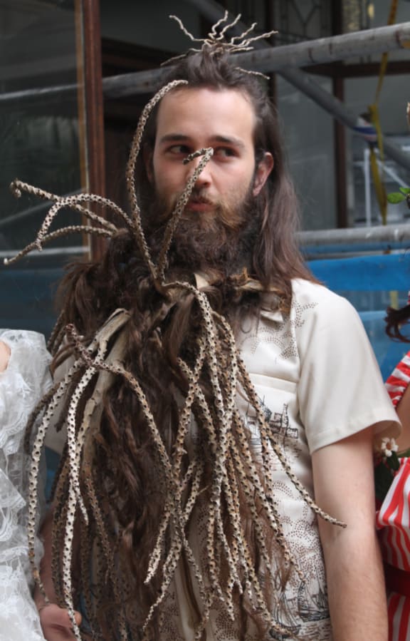 An image of a performer wearing long twigs woven into his hair and beard.