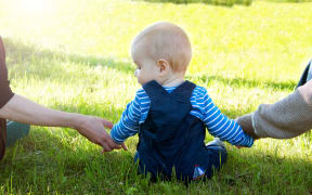 Baby with mother and father holding hands on the nature