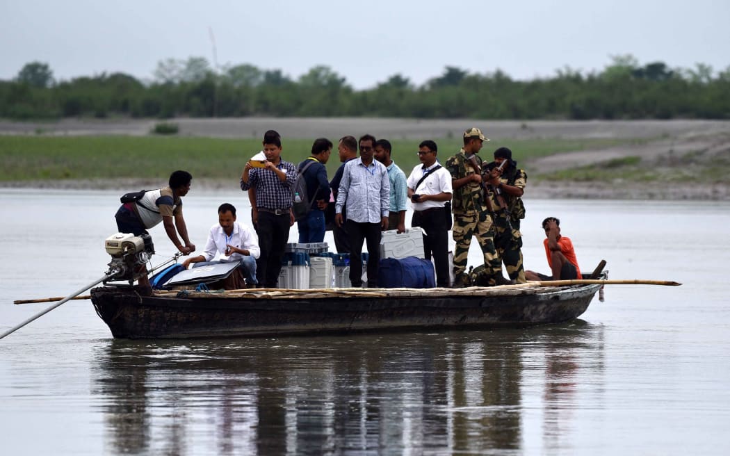 Polling officials and security personnel are carrying Electronic Voting Machines (EVMs) and other polling materials on a boat to a polling station at Lohore Chapori in Golaghat district, India, on April 18, 2024. (Photo by Anuwar Hazarika/NurPhoto) (Photo by ANUWAR HAZARIKA / NurPhoto / NurPhoto via AFP)