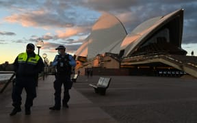 Police officers walk past The Sydney Opera House during the first day of lockdown in Sydney, Australia.