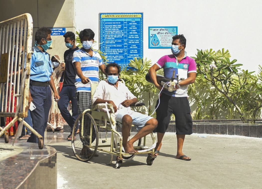 A covid-19 patient with an oxygen cylinder can be seen outside covid-19 ward of a government hospital in Kolkata, India, 20 April, 2021. Covid-19 patient family members wait outside covid-19 ward of a government hospital in Kolkata, India, 20 April, 2021.