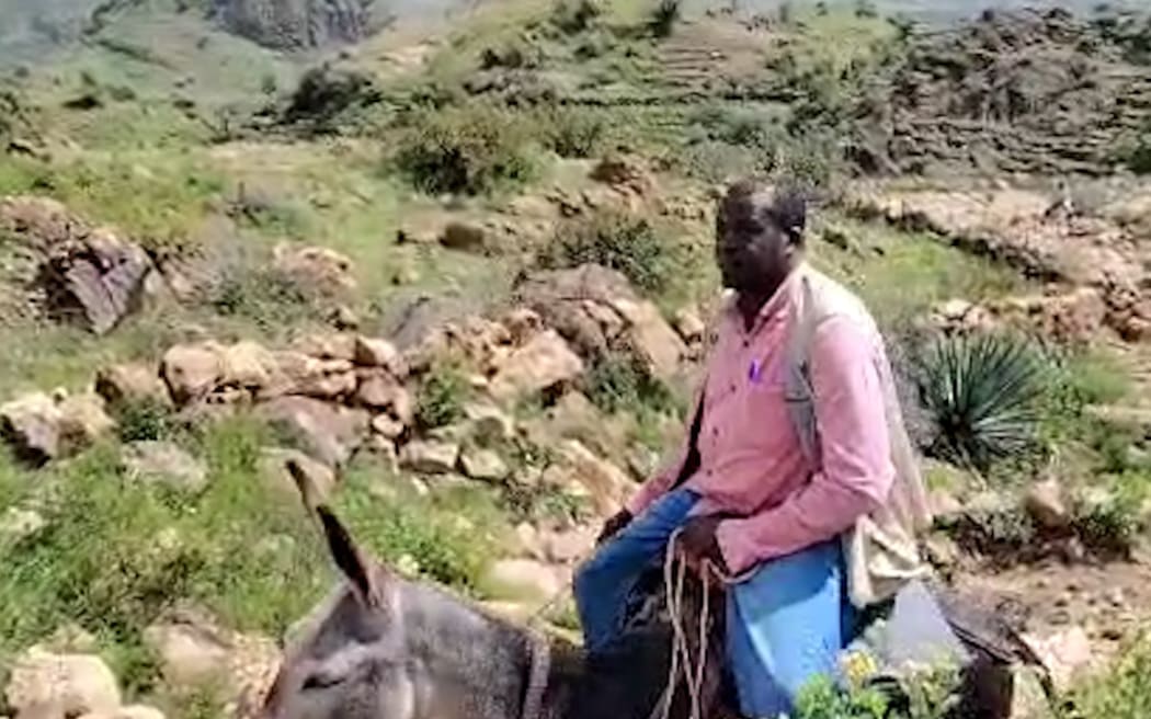 A man rides a donkey through rocky, muddy terrain in Sudan's Marra Mountains.