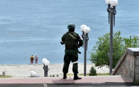 In this file photo taken on May 20, 2022 a Russian serviceman patrols at a river bank in Kherson, amid the ongoing Russian military action in Ukraine.