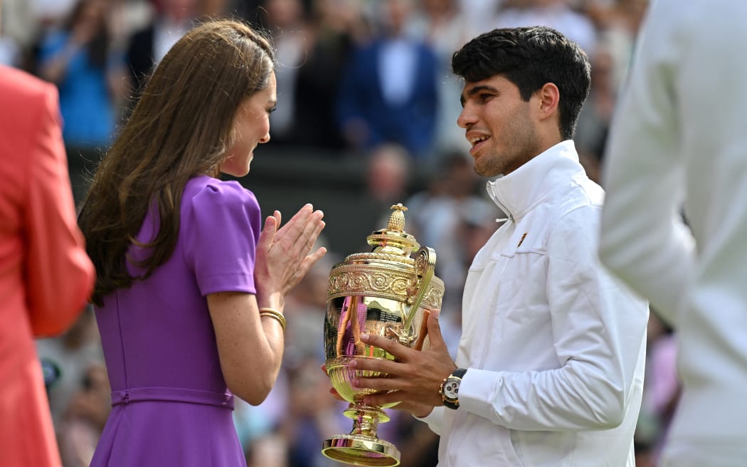 Britain's Catherine, Princess of Wales congratulates Spain's Carlos Alcaraz as he receives the winner's trophy after beating Serbia's Novak Djokovic during their men's singles final tennis match on the fourteenth day of the 2024 Wimbledon Championships at The All England Lawn Tennis and Croquet Club in Wimbledon, southwest London, on July 14, 2024. Defending champion Alcaraz beat seven-time winner Novak Djokovic in a blockbuster final, with Alcaraz winning 6-2, 6-2, 7-6. (Photo by ANDREJ ISAKOVIC / AFP) / RESTRICTED TO EDITORIAL USE