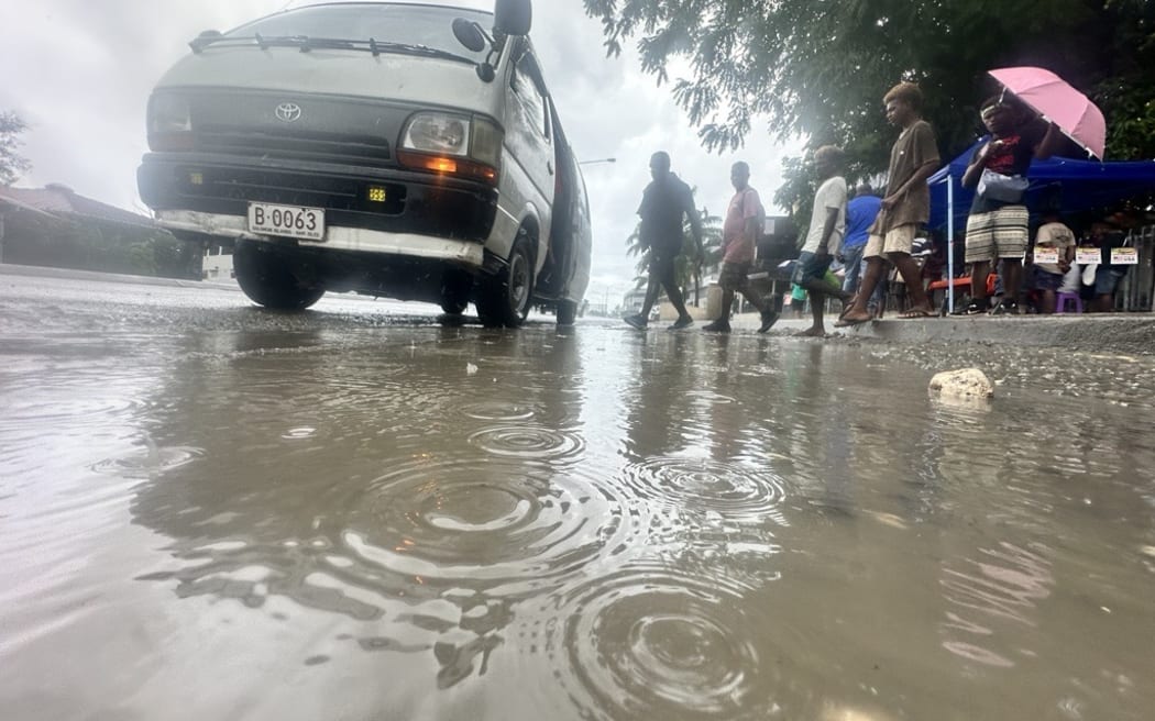 Commuters jump over a puddle to board a bus at Point Cruz in the Solomon Islands capital Honiara. 16 April 2024