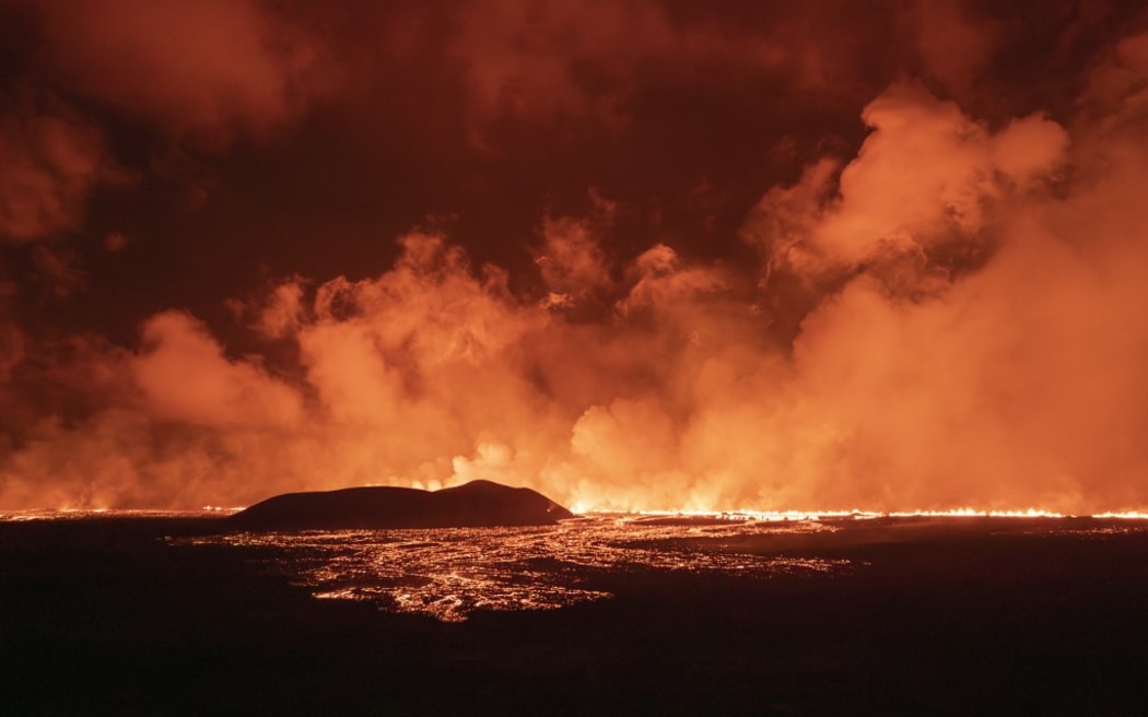 A photo taken during the night from August 22 to 23, 2024 shows lava and smoke erupting from a volcano near Grindavik on the Icelandic peninsula of Reykjanes. A new volcano erupted on the Reykjanes peninsula in southwestern Iceland on August 22, 2024, spewing hot lava into the air in the sixth eruption to hit the region since December 2023, authorities said. (Photo by Ael Kermarec / AFP)