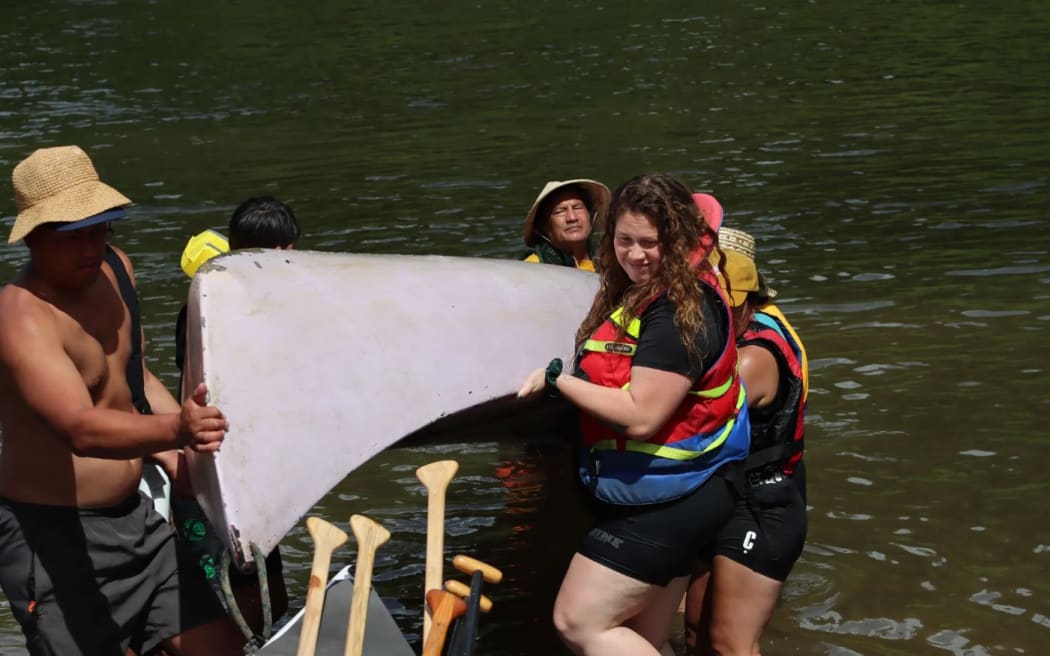 Kaihoe (paddlers) carry their six-man Canadian canoe from the Whanganui River at Ōhinepane. Photo: Tuakana Te Tana (single use only)