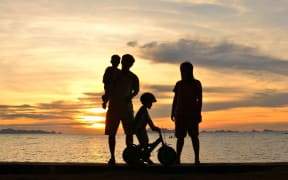 silhouette of family on the beach at dusk.