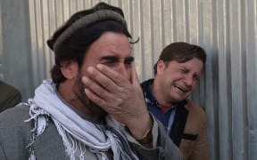 Two Afghan men weep for their relatives after gunmen dressed as doctors killed more than 30 people at a Kabul hospital.