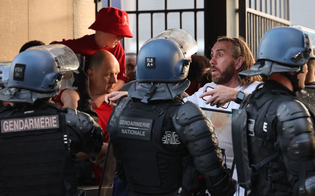 Police stand in front of fans prior to the UEFA Champions League final football match between Liverpool and Real Madrid at the Stade de France in 2022.