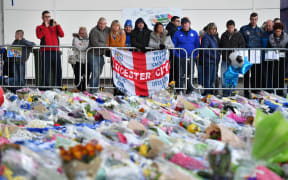 Supporters pause at the pile of floral tributes outside Leicester City Football Club's King Power Stadium.