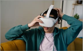 Image of a woman wearing a VR headset while sitting on a couch.