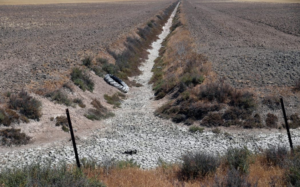 This picture taken on May 11, 2023 shows a dry drainage channel of crops fields, at the Donana National Park in Aznalcaraz, southern Spain. Spain's government today approved measures worth more than two billion euros to alleviate the impact of a prolonged drought that has hit its key agricultural sector. The country's water reserves are on average below 50 percent of capacity, while levels have fallen to roughly 25 percent in the two worst-hit areas –- Andalusia in the south and Catalonia in the northeast. (Photo by CRISTINA QUICLER / AFP)