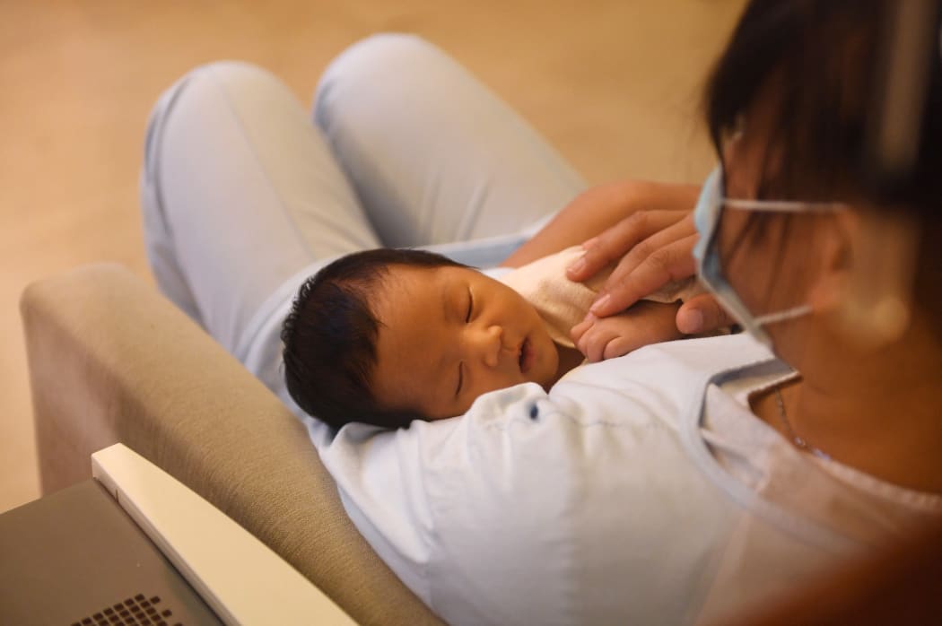 A nurse holds a baby at the Xiyuege Centre, or "Lucky Month Home", in Beijing. Concerns about slow population growth led to a three-child policy in May this year.