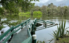 Waikato River water levels high, almost reaching the top step of a jetty.