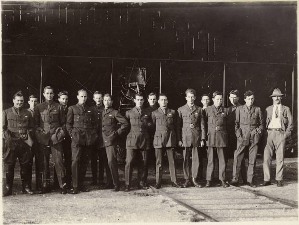 An image of 15 Flying School pilots in NZFS uniform standing in front of a plane in a hangar.