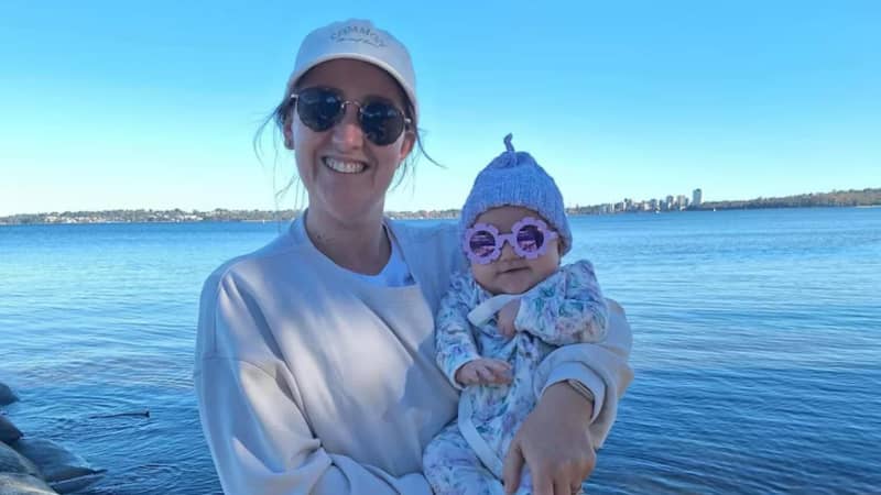 Melanie Connell holding a baby at a beach.