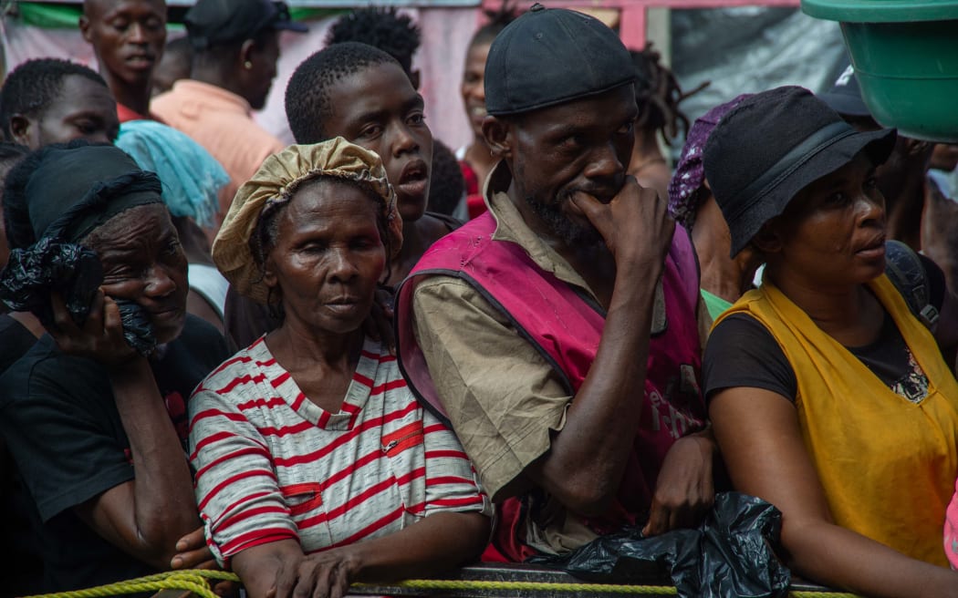 People wait for a food distribution in a displaced persons camp at the Lycée Marie Jeanne in Port-au-Prince on September 30, 2024. - The UN Security Council extended on Monday its authorization of the multinational policing mission in crime-ravaged Haiti, but without any call to transform it into a UN peacekeeping mission, as floated by Port-au-Prince. (Photo by Clarens SIFFROY / AFP)