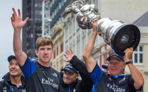 Team New Zealand helmsman Peter Burling and Team New Zealand Boss Grant Dalton hold aloft the Americas Cup during the Team New Zealand victory Parade in Auckland in July 2017.