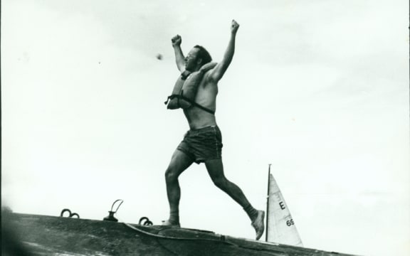 n image of Stephen Sherie on the hull of the USS Haddo, arms raised aloft.