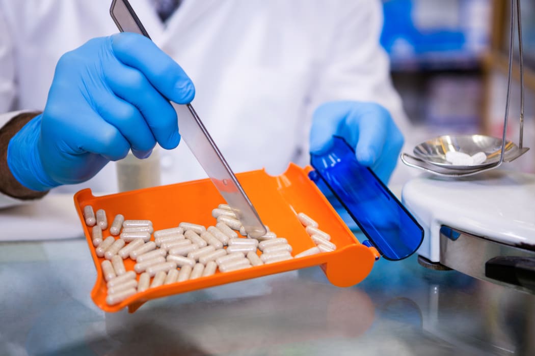Pharmacist putting pills in container at pharmacy.