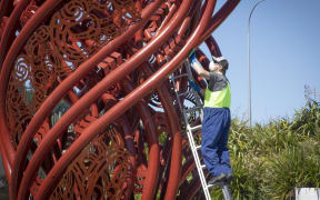 A man fixes the Hemo Gorge roundabout sculpture.