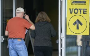People enter a polling place on election day in Ottawa, Canada on April 28, 2025. Canada was voting Monday for a new government to confront a trade war and annexation threats by President Donald Trump, who pushed for the United States to absorb its neighbor as polling stations opened.  The Liberal Party, led by new Prime Minister Mark Carney, looked set to lose to the Conservatives' Pierre Poilievre until the US president's attacks on the country sparked a sudden reversal in poll forecasts. Trump forcefully inserted himself into Canadian politics on election day with a Truth Social post saying Canada would face "ZERO TARIFFS" if it "becomes the cherished 51st state." (Photo by Geoff Robins / AFP)