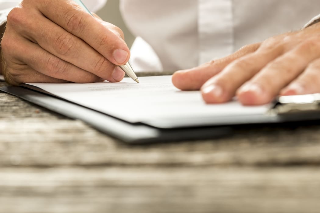 A man in a white business shirt signs a job offer or contract (file)