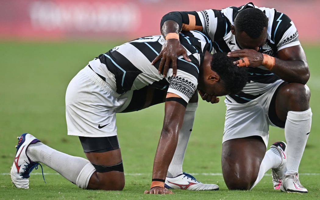 Fiji's Napolioni Bolaca (L) reacts with a teammate after winning the men's final rugby sevens match between New Zealand and Fiji during the Tokyo 2020 Olympic Games at the Tokyo Stadium in Tokyo on July 28, 2021.