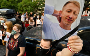 A picture of Vitaly Shishov is held by an activist as he takes part in a rally outside the Belarus embassy in Kiev on August 3, 2021.