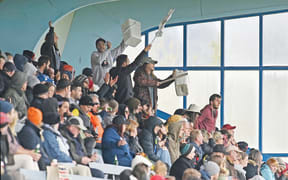 Thistle fans in the stand at Childers Road Reserve take to their feet to cheer on their players.